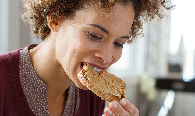 A women eating a piece of toast with her dentures