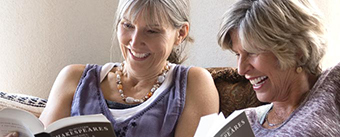 Two smiley women reading